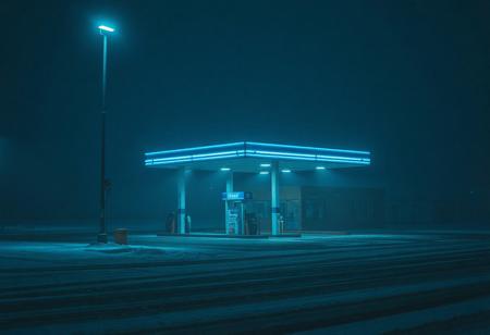 A desolate winter gas station under a blue streetlamp, snowfall, minimalistic architecture, foggy and quiet, vaporwave aesthetic, liminal space art, 4K resolution