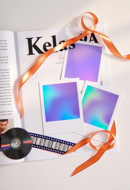 create A modern FLAT LAY collage magazine design with semi-realistic illustration featuring the text 'Kelas 9A'. The scene is viewed from a top-down perspective.must look flat without shadow, showing 3 iridescent polaroid Photo with different size, the 3 photos must straight ortogonal angle in white paper. rose-gold-ribbon as ornament. negative film strip and disc next to it. Iridescent light radiates across the scene, creating a warm atmosphere. vibrant, iridescent colors