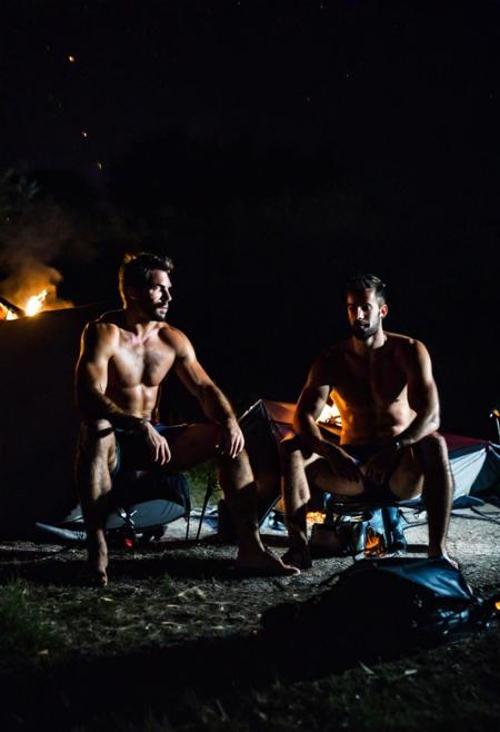 Two hairy chested fit italian men in a campsite, shirtless, sitting in a camping tend, a fire lit in front of the tent, in a dark night, extreme close up photo, moonlight
