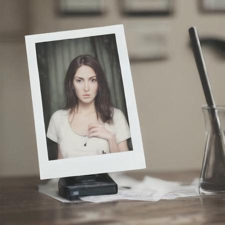 highly realistic adult woman standing up as a glossy polaroid lying on the table  <lora:glossyphotov3-notfullytrained:0.7>