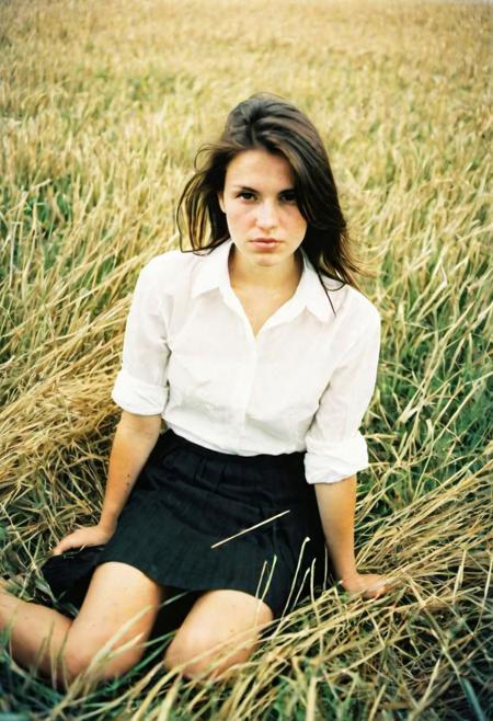 european woman 25 years sitting in a grass field, long grass straw, black skirt, white shirt,from top,half body, kodak ektar e100 analog film, artsy, harsh shadows, ultra wide angle, contact test, damaged print,flash,overexposed, faded, light leaks on print,grainy,blurry, pixelated, motion blur, vignette