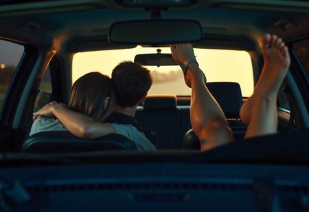 view of front of car at drive-in movie, screen lighting through the windshield dimly the front seat, where a 18yo couple have their heads leaning together, his arm around her shoulders, and  lighting the back seat where a woman's widespread bare legs are sticking up in the air, shoe hanging from one foot. pov: movie screen facing car. 
, very detailed, detailed eyes,  high detailed texture, realistic, photorealistic, perfect eyes, real life realistic,  detailed background,