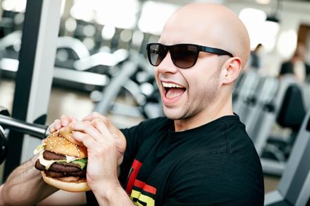 <lora:Eatingburger:0.5>, food focus, eating a burger, smile, open mouth, male, side view, two hands, looking at viewer, ((bald)), sunglasses, ((gym)), ((solo))