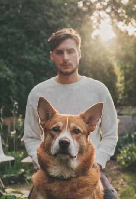 cinematic film still fashion photography portrait of 1man with dog as companion, grainy, headshot, sunlight , Fine Art & Beauty Photography – ,,light diffraction in frame, dreamy,hazy look.  Helios 44-2 lens mounted on a Praktica MTL 5B Helios 44M-4 lens, 58mm f/2,   in a garden.