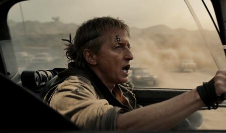 Johnnylawrence person <lora:JohnnyLawrence-Lora:.8> driving in a /"Mad Max style"/ buggy. (tough guy facial expression)