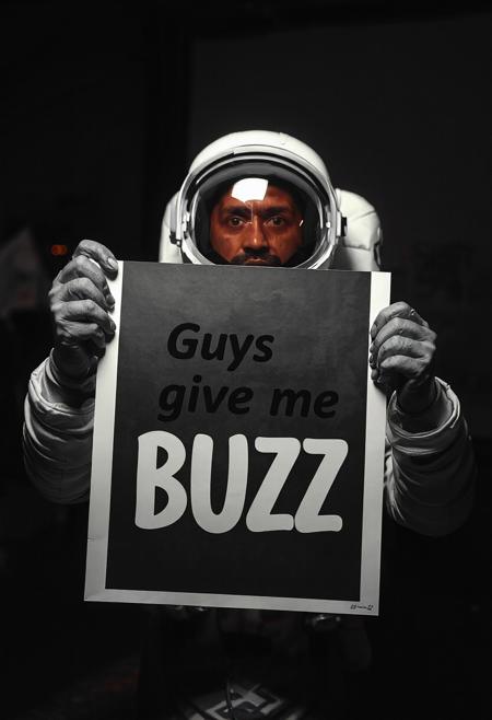 cosmonaut holding poster, text on a poster "Guys give me BUZZ"