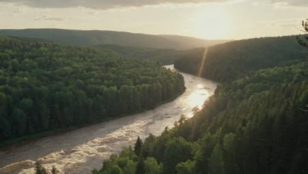 The camera pans over a sprawling landscape of towering trees, rolling hills, and flowing rivers, the sun hanging high in the sky. Birds chirp in the distance, and the wind rustles through a nearby forest, 80s movie<lora:vhs_footage_4-10:1.0>