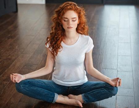 realistic masterpiece glamour instagram photograph of Alina01 sitting in a meditation pose on a hardwood floor, eyes closed, wearing a tight fitting white tshirt and blue jeans, long curly natural red hair, {freckles1.1}, petite body