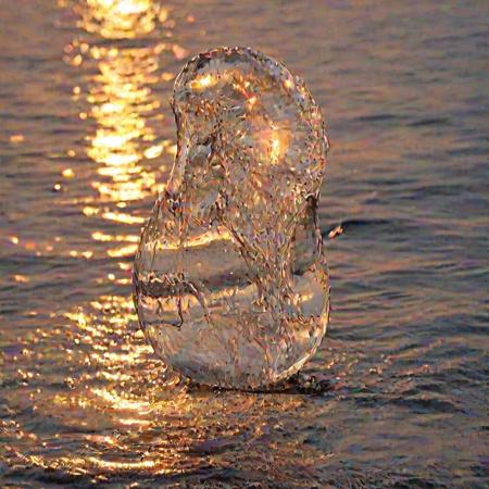 a crystal clear drop of water splashes into the sea,  sunset, macro photography, melting reaction