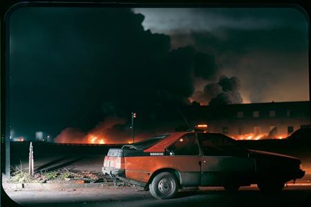 analog gloomy photo of a red Renault Fuego car, <lora:fu3g0:1>, chased by police in the city (at night), urban street ruins in the background, fire and smoke, explosions in the back, nighttime, High Detail, Sharp focus, ((photorealism)), flares, realistic, best quality, 8k, award winning, dramatic lighting, epic, cinematic, masterpiece, depth of field,