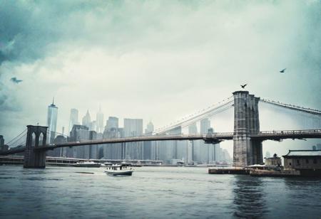 Brooklyn Bridge, New York City, overcast sky, birds flying, cityscape, river, suspension bridge, stone pillars, historical structure, moody atmosphere, blue color tone, cloudy weather, urban environment, architectural landmark, travel destination, waterscape, boat on river, heavy clouds, cyanotype filter, daytime.