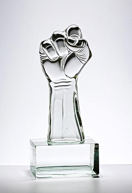 A clear glass sculpture of a raised fist showing the middle finger