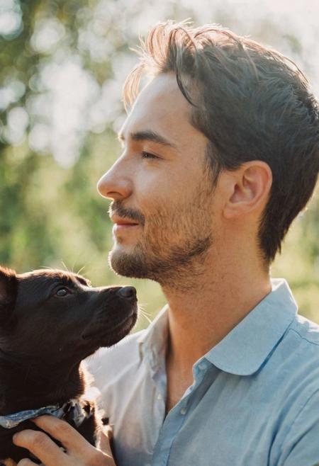 cinematic film still fashion photography portrait of 1man with cute dog as companion, headshot, sunlight , Fine Art & Beauty Photography – ,,light diffraction in frame, dreamy,hazy look.  Helios 44-2 lens mounted on a Praktica MTL 5B Helios 44M-4 lens, 58mm f/2,   in a garden. authentic happy smile towards camera, <lora:hand 4:0.3>