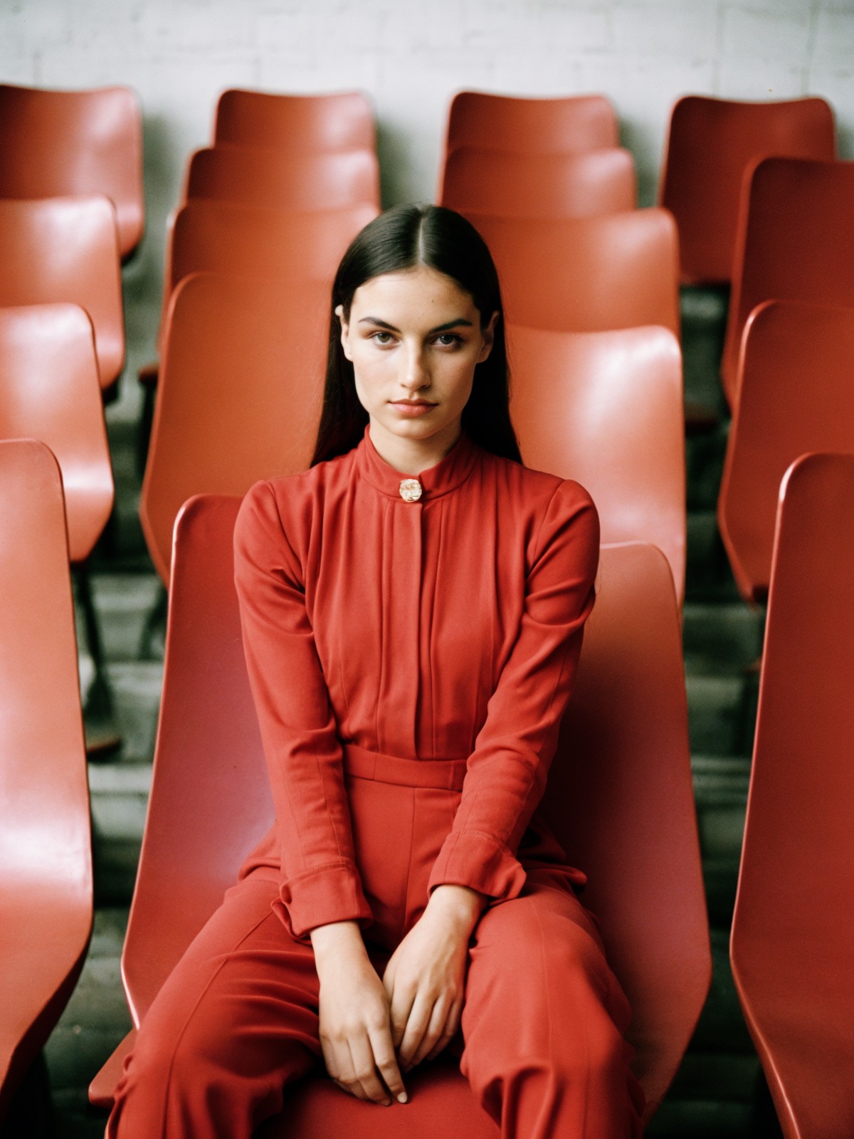 film grain analog photography,poised woman fair complexion, dressed vibrant red jumpsuit full sleeves black collar detail,...