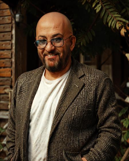 shufutinskiy man standing in knitted blazer, bald, smile, glasses, (fat:1.0), look in camera, old russian house on background, medium shot, (close up:0.4), classic chrome, film grain, soft lighting,  bokeh  <lora:3rd_september_v1:0.75> <lora:AdvancedEnhancer:1.0>