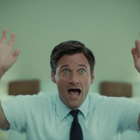 movie still, interior shot of a man in a room talking with his hands in the air