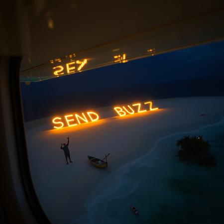 n a small Cessna airplane, looking down on a deserted island  in midnight when you see something strange on the beach. the wood burning to form the word "SOS SEND BUZZ" had been lit up . A man is on the beach waving his arms. There is a small shipwrecked boat on the beach.
The frame of the airplane window and the wing are visible. There is a large clump of palm trees on the beach.