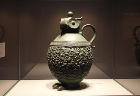Inside a museum display case is a (single:1.4) 3000 year old Ancient bronze ewer from Shang dynasty of China. The ewer  is much taller than it is wide.    The ewer is formed in the shape of a stylized owl. The lid of the ewer forms the beak of the owl. the beak and eyes of the owl are the same color as the rest of the owl. It has a handle on the back.  instead of feathers, the body of the owl, and the entire ewer, is decorated in (intricately detailed and complex ancient chinese monster_taotie motifs:1.5).  The ewer is made of heavily oxidized bronze that appears green because, and the metal has corroded and crusted in minerals over the centuries since it was crafted.