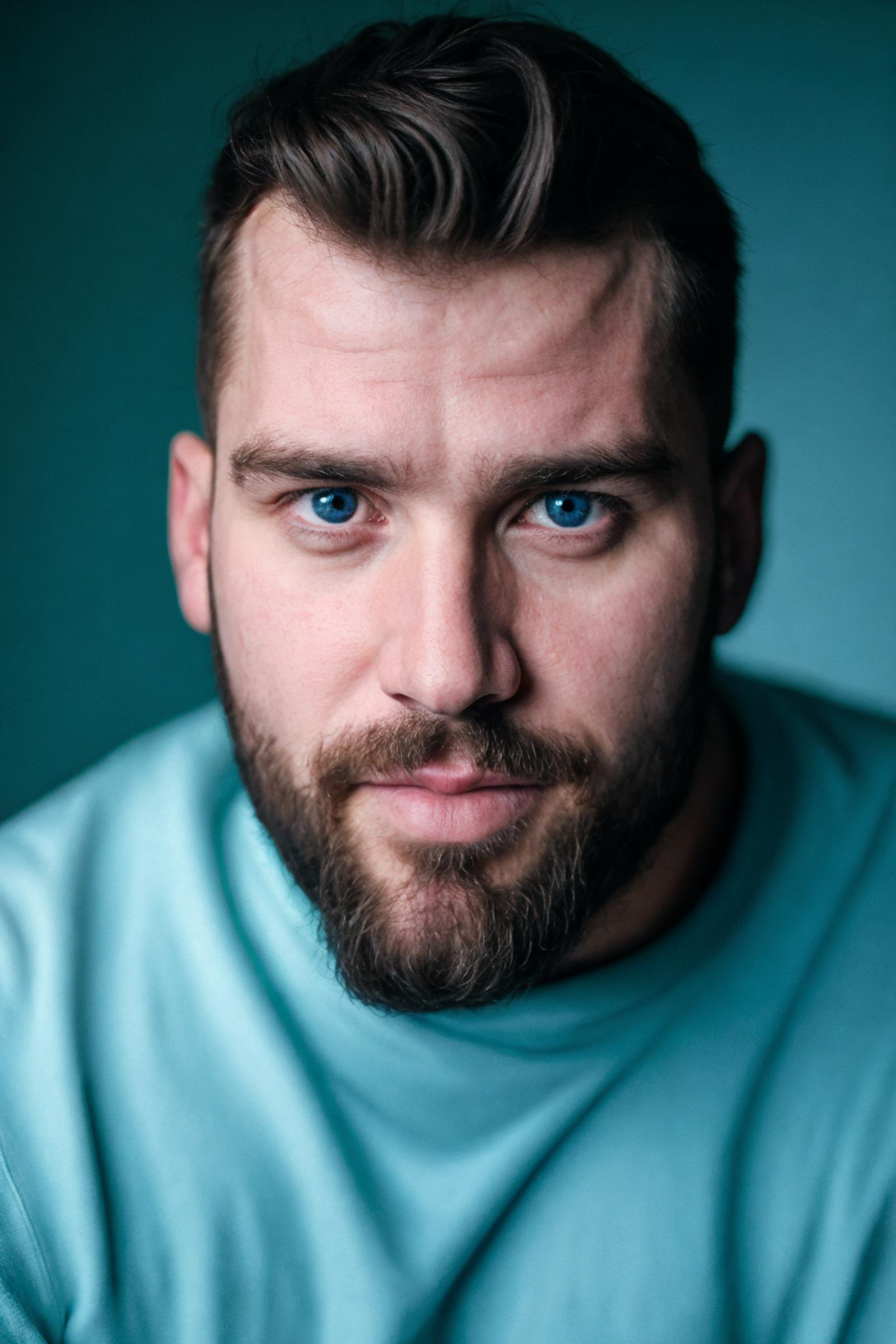 Man with blue eyes and beard in a blue shirt.