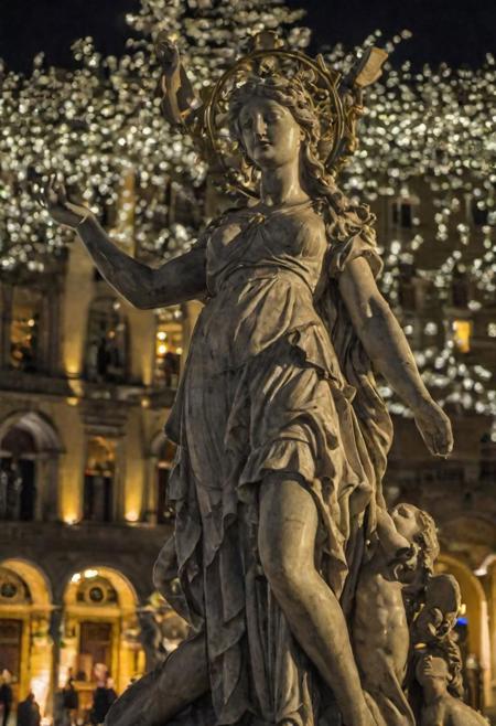 A very detailed masterpiece statue of a goddess holding symbolic artefacts in many hands, marble pulsating in luscious town square with a crowd of people, night time, parted lips, in style of Donatello and Michelangelo, detailed textures, bokeh, night lighting, 4k uhd, dslr, soft lighting, high quality, Fujifilm XT3