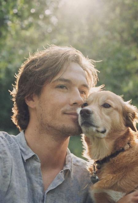 cinematic film still fashion photography portrait of 1man with cute dog as companion, headshot, sunlight , Fine Art & Beauty Photography – ,,light diffraction in frame, dreamy,hazy look.  Helios 44-2 lens mounted on a Praktica MTL 5B Helios 44M-4 lens, 58mm f/2,   in a garden. authentic happy smile towards camera, <lora:hand 4:0.3>