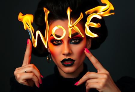 A very young drag queen girl with black makeup and pink nails, looking like she just failed something, shaking her head, drawing the letters "Woke" using flamess, in the air, with a finger, photo by helmut newton