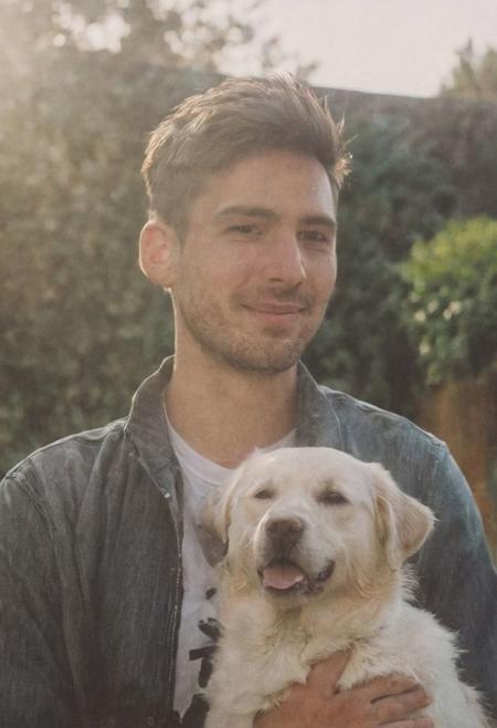cinematic film still fashion photography portrait of 1man with dog as companion, grainy, headshot, sunlight , Fine Art & Beauty Photography – ,,light diffraction in frame, dreamy,hazy look.  Helios 44-2 lens mounted on a Praktica MTL 5B Helios 44M-4 lens, 58mm f/2,   in a garden. authentic happy smile