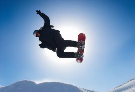 man doing a snowboard stunt, background a sunny blue sky