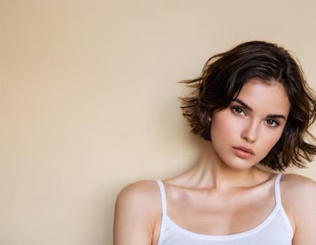 photo of a young woman with short, tousled dark hair. She has fair skin and captivating dark eyes, brown eyes, perfecteyes. The face has a soft, oval shape with slightly angular cheekbones. The nose is straight with a delicate bridge, and the tip is slightly rounded. The lips are full, with the upper lip showing a defined cupid's bow. The lower lip is slightly fuller than the upper one. She has a smooth, fair complexion 

