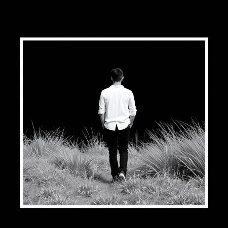 The image shows a black and white photo of a person in a white shirt and black pants, standing in front of a black background. The person is surrounded by a grassy landscape, giving the photo a peaceful and serene atmosphere.