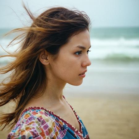 candid photo of M02AWA, windy hair, boho dress, no makeup, close up, from side, looking away, shot with Canon EOS 5D on kodak portra 400, blurry background, on a beach