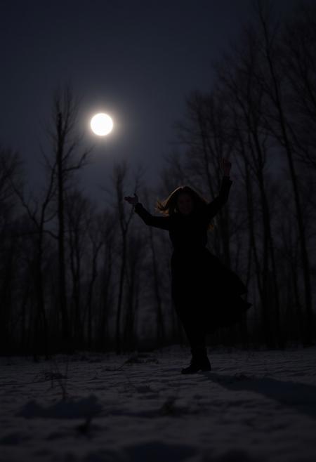 a woman dancing in a cold winter night  on a clearing in the woods under a full moon