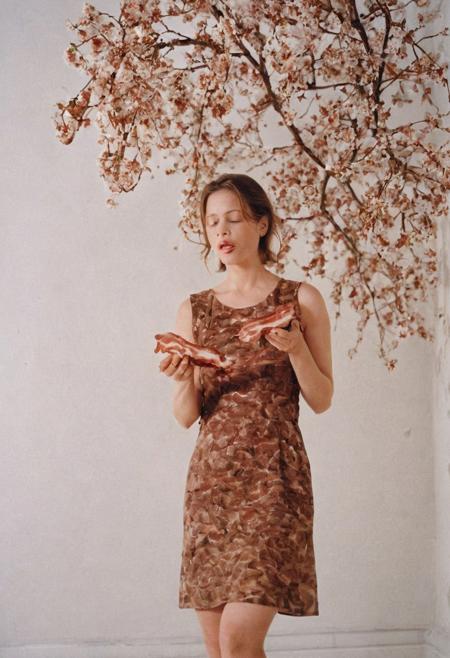 Model photography, the 1990s, bacon, a tree with bacon leaves, beautiful, in a white room, beautiful bacon blossom tree, a female eating bacon, wearing a brown dress, white lighting, film grain, DSLR