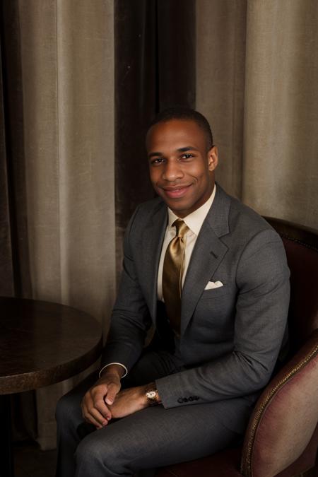 RAW Photo, photo of (light-skinned) African American man sc_chad3 <lora:sc_chad3-06:1> sitting introspectively in a booth in a Parisian-style cafe, contemplative smile, wearing charcoal tailored (tom ford suit) with ivory dress shirt and silk burgundy gucci tie with gold accents, deep mahogany walls,  ambient glow, dim interior, soft daylight filtering through lace curtains,serene atmosphere, nostalgic atmosphere, (vanity fair magazine), (photo by Sebastião Salgado)