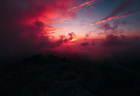 A crimson-hued sunset descends upon a rugged terrain, where wispy clouds and misty fog envelop the landscape in an eerie atmosphere. A dark, muted palette dominates, with deep oranges and purples bleeding into the distant haze. Cinematic lighting casts long shadows, imbuing the scene with dramatic tension. The camera pans across the terrain, capturing every nuance of fine detail, from the wispy grasses to the weathered rocks. A masterpiece of composition and atmospheric mastery, this breathtaking image demands attention.