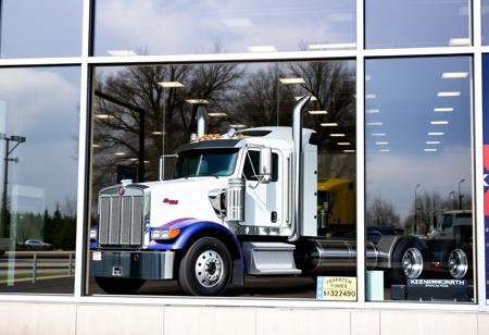 In the window of a large Kenworth 4S store sits a Kenworth W990 truck