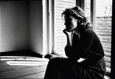 european woman 30 years old sitting in front of a window, watching outside, face in shadow, low light, full body shot from side, 1990 hairstyle and look, dark mood, ilford hp5 plus 400, medium format camera,artsy, shadows, wide angle, contact test, damaged print, faded, grainy,blurry, pixelated, motion blur, vignette, high contrast