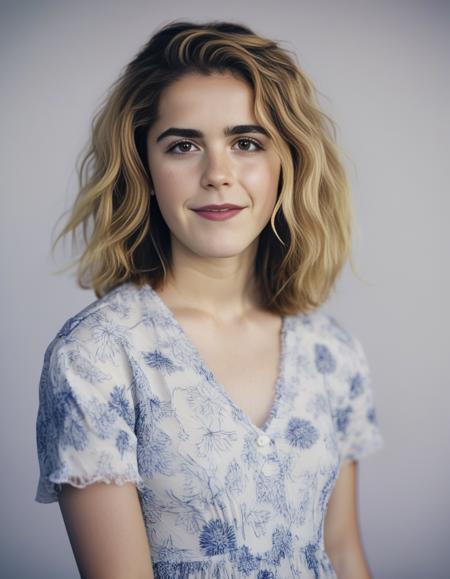 KiernanShipka,<lora:KiernanShipkaSDXL:1>,A portrait of a woman with full, curly hair and fair, freckled skin. She has light-colored eyes and wears minimal makeup. Her expression is serene and self-assured. She is dressed in a blue and white floral V-neck dress. The setting suggests a beach atmosphere, with soft natural light enhancing her features.