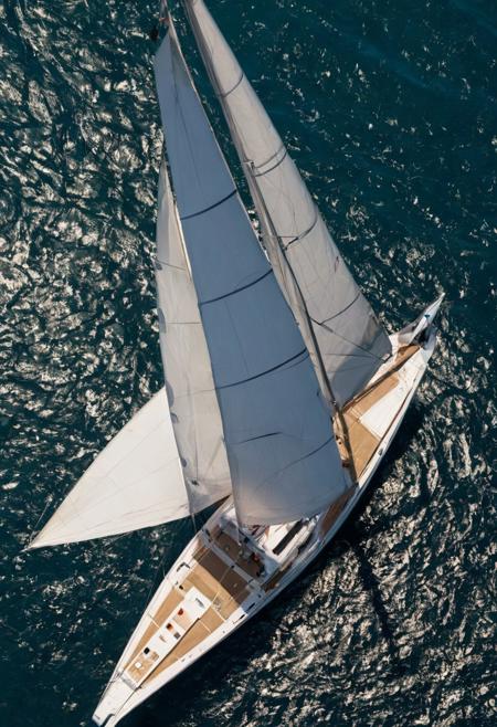 aerial shot, white, blue and gold colored racing yacht in a regatta, azure blue waters