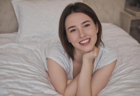 Smiling, sexy 20yo girl laying on a bed looking at the viewer