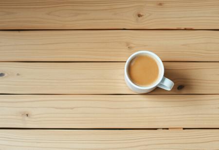 A view from the top of a wooden table with a coffee mug, classic stock photo, chill vibe, latte cafe on a classic wooden kitchen table. Empty table except the coffee mug. Coffee mug on the far right. Clean mug with fresh coffee, light foam on coffee. No space between plank, glued plank without gaps