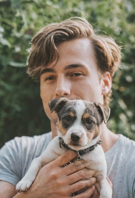 cinematic film still fashion photography portrait of 1man with cute dog as companion, headshot, sunlight , Fine Art & Beauty Photography – ,,light diffraction in frame, dreamy,hazy look.  Helios 44-2 lens mounted on a Praktica MTL 5B Helios 44M-4 lens, 58mm f/2,   in a garden. authentic happy smile towards camera, <lora:hand 4:0.3>