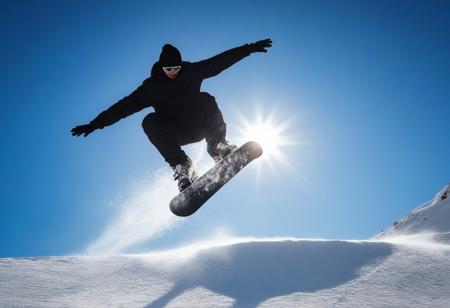 man doing a snowboard stunt, background a sunny blue sky