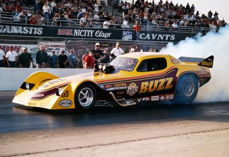 VintageMuscleCar, dragster, side view, race track, smoke trail, people, outdoors, 4K, highly detailed, (stylish grainy analog 35mm film photo, "BUZZ")