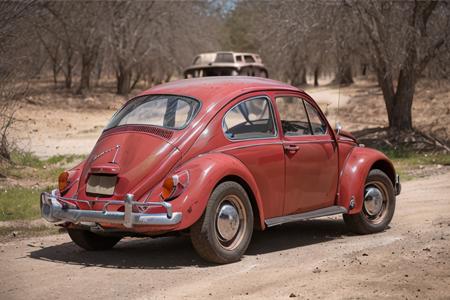 analog gloomy photo of a red Volkswagen Beetle car, <lora:vwb33tl3:1>, back view, (dark sunset), driving on a dirt road, (decayed and dilapidated town), 1969, ((horror movie)), slasher film, texas chainsaw massacre, film grain, retro,  High Detail, Sharp focus, ((photorealism)), realistic, best quality, 8k, award winning, dramatic lighting, epic, cinematic, masterpiece