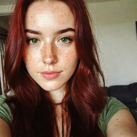 instagram selfie, ((upper body)), a 23 year old gorgeous woman, busty, slight smirk, detailed skin face and eyes, natural lighting, at home, long hair, low contrast, natural face, freckles, dark red hair, green eyes