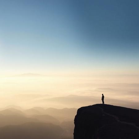 A vast, misty landscape at dawn, with mountains fading into the distance, symbolizing the expansive, emotive quality of post-rock music, with soft, ethereal lighting and a lone figure standing on a cliff, contemplating the view, dreamlike atmosphere, muted colors.
