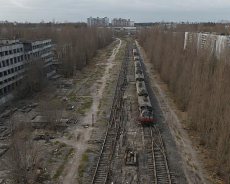 best quality, realistic, vray, hdr, a train track running through a city with tall buildings, Chern4byl enviroment  <lora:PostApocalyptic_Chernobyl_v3:0.8>