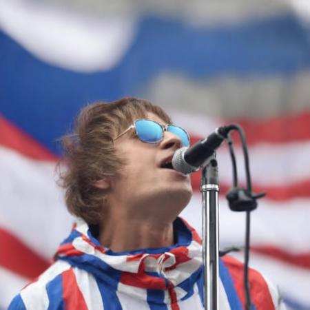 a photo of Li4mG4ll4gher, singing into a microphone, red white and blue parka, wearing sunglasses, 4k, ultra detailed, masterpiece,  <lora:Li4mG4ll4gher:1.2>