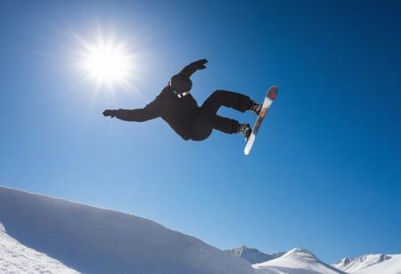 man doing a snowboard stunt, background a sunny blue sky